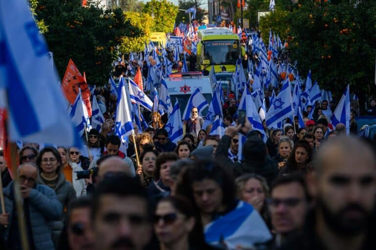 Thousands of people line the street to watch and pay their respects as the funeral procession carrying the caskets of Shiri Bibas, Kfir Bibas and Ariel Bibas pass by with the family in minibuses behind them on its way to the funeral on February 26, 2025 in Rishon LeZion, Israel.