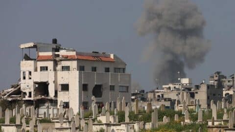 Smoke billows behind a cemetery (foreground) during Israeli strikes west of Gaza City on March 18, 2025.