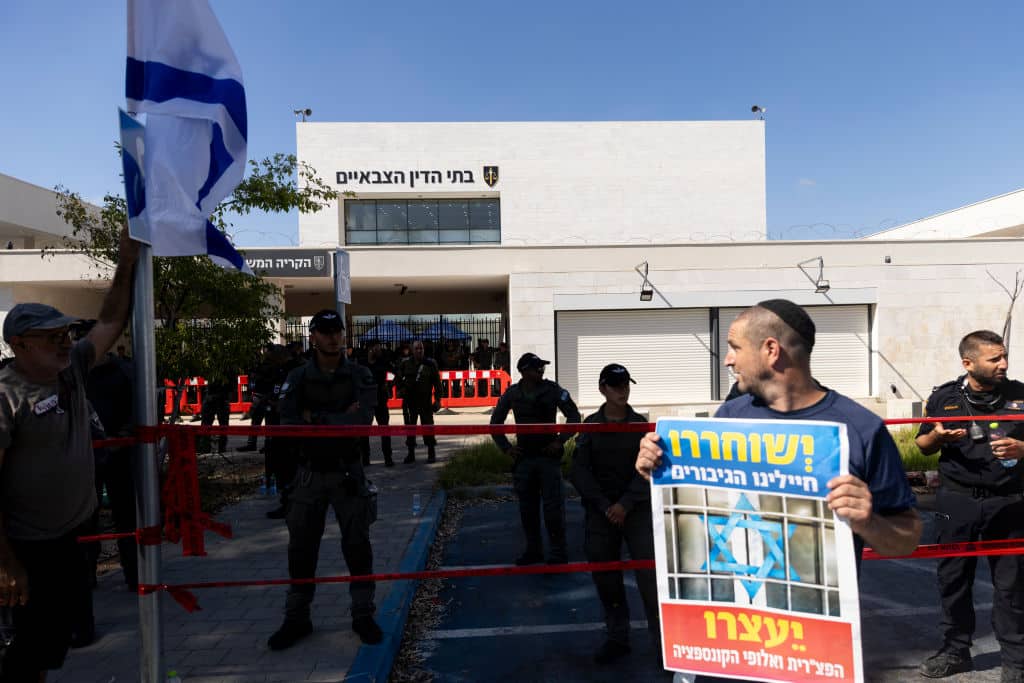 Protesters hold signs and flags during a demonstration against Israeli military prosecutors  near a military court  on July 30, 2024 in Kfar Yona, Israel.