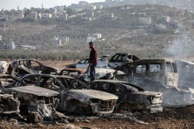 A Palestinian checks a vehicle scrapyard after Israeli settlers burned it in the town of Huwara, south of the West Bank city of Nablus, on Nov. 21, 2025. According to the official WAFA news agency, Israeli settlers set fire to a vehicle scrapyard here on Friday evening. (Photo by Ayman Nobani/Xinhua via Getty Images)