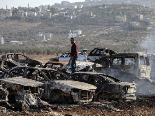 A Palestinian checks a vehicle scrapyard after Israeli settlers burned it in the town of Huwara, south of the West Bank city of Nablus, on Nov. 21, 2025. According to the official WAFA news agency, Israeli settlers set fire to a vehicle scrapyard here on Friday evening. (Photo by Ayman Nobani/Xinhua via Getty Images)