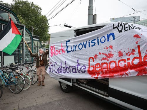 An activist stands next to a banner reading "Block Eurovision" to protest against the participation of Israel ahead the first semifinal of the Eurovision Song Contest, Vienna, Austria, on May 12, 2026. (Photo by Radek MICA / AFP via Getty Images)