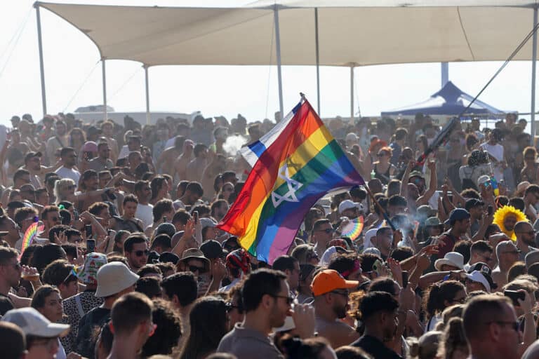 A participant waves an Israeli flag and a rainbow flag with a Star of David above a crowd during the annual Pride Parade in Tel Aviv, Israel, on June 12, 2026. The event marks the 28th edition of the parade and the first since the October 7 attacks. Recognized as the largest Pride march in the Middle East, the gathering in the Israeli coastal metropolis was expected to draw around 150,000 people. (Photo by Simon Beni / Middle East Images / AFP via Getty Images)