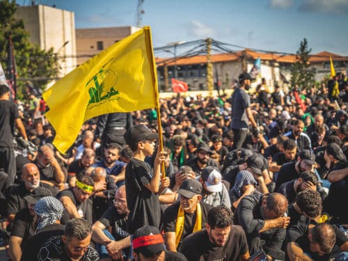 A boy holds a yellow Hezbollah flag while walking among a crowd during a mourning ceremony in the southern suburbs of Beirut, Lebanon, on June 26, 2026. The event, organized by Hezbollah, marks Ashura, a period culminating on the tenth of the Islamic month of Muharram that commemorates the seventh-century killing of Prophet Mohammed's grandson, Imam Husayn. (Photo by Nael Chahine / Middle East Images / AFP via Getty Images)