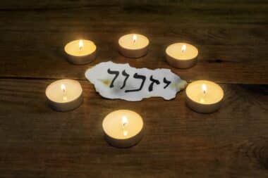 Candles surrounding the word "Yizkor" meaning "may He remember."