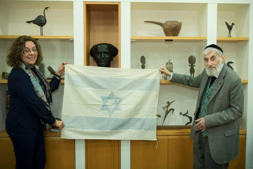 Rebecca Affachiner’s handsewn flag, being presented to then Ben-Gurion University President Prof. Rivka Carmi by Affachiner’s heir, Ezra Gorodesky, in 2018. Photo by Dani Machlis/BGU