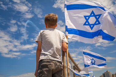 A boy watches the Israel Air Force perform the annual fly by on Independence Day from the beach. Photo by Roman Yanushevsky via Shutterstock